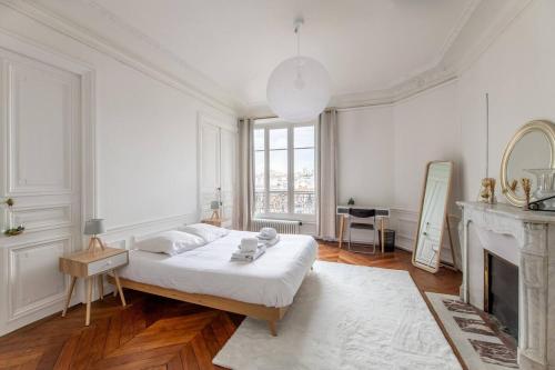 une chambre blanche avec un lit et une cheminée dans l'établissement Stunning Parisian Getaway, à Paris