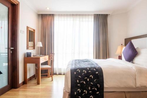 a hotel room with a bed and a desk and a window at Plaza Sutera Biru Hotel in Kuala Belait
