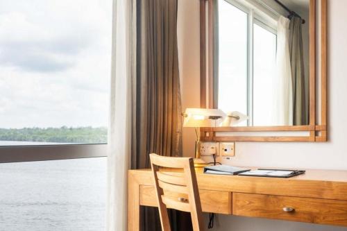 a desk with a mirror and a window at Plaza Sutera Biru Hotel in Kuala Belait