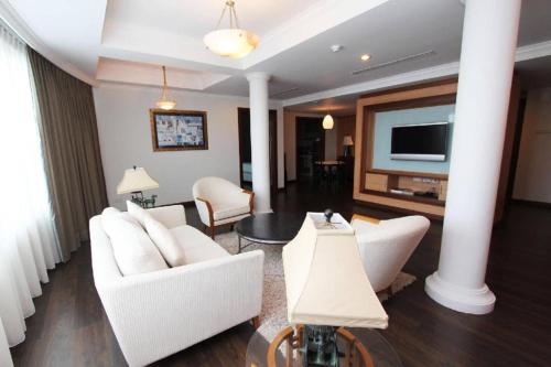 a living room with white furniture and a flat screen tv at Plaza Sutera Biru Hotel in Kuala Belait