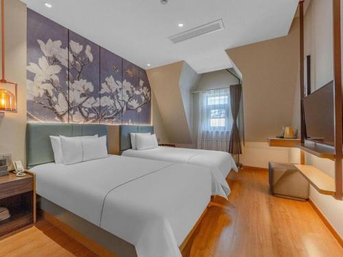 a bedroom with two beds and a painting on the wall at Magnotel Business Qufu Sankong Scenic Area Chunqiu West Road in Jining