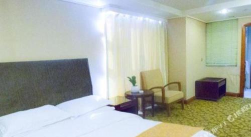 a hotel room with a bed and a chair at Jincheng Pacific Hotel in Jincheng