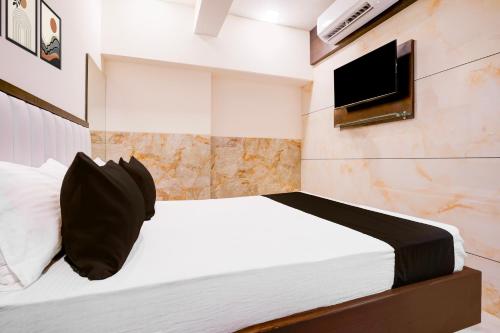 a bedroom with a bed with a tv on the wall at Super Collection O Kalyan East in Ulhasnagar