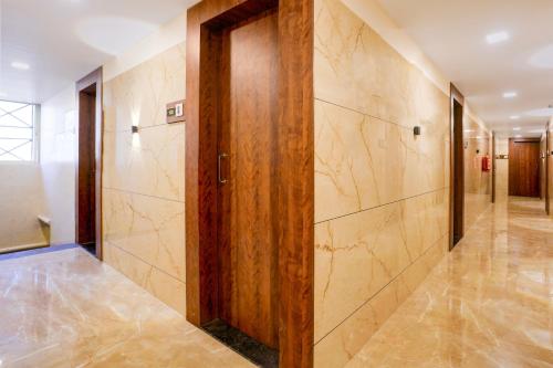 a hallway with a wooden door and marble walls at Super Collection O Kalyan East in Ulhasnagar