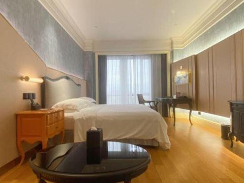 a bedroom with a bed and a table and a desk at Zhejiang D.H Hotel in Jiaxing