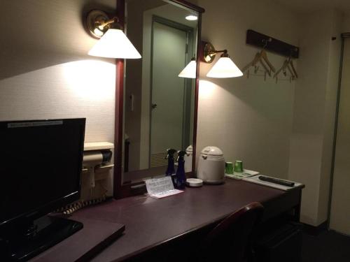 a desk with a mirror and a desk with a television at Hotel Town Nishikigawa in Kochi