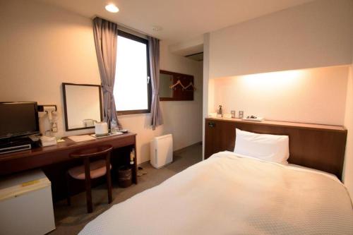 a bedroom with a bed and a desk and a computer at Hotel Matsuya in Shimanto