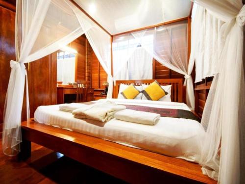 a bedroom with a canopy bed with white sheets and pillows at Phimai Paradise House in Pi Mai