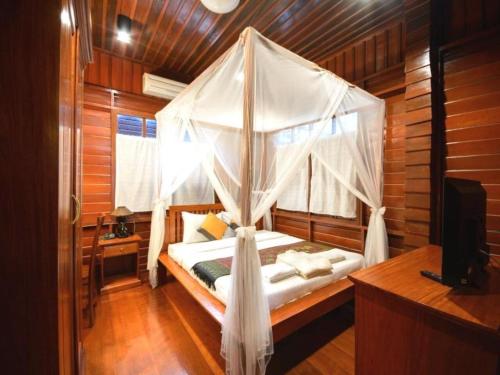 a bedroom with a canopy bed with a television at Phimai Paradise House in Pi Mai