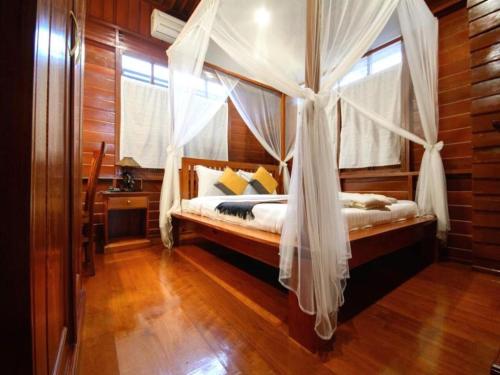 a bedroom with a canopy bed with a window at Phimai Paradise House in Pi Mai