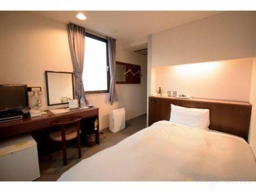 a bedroom with a bed and a desk and a computer at Hotel Matsuya in Shimanto