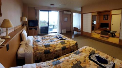 a hotel room with two beds and a mirror at Kirishima Onsen Ryokojin Sanso in Kirishima