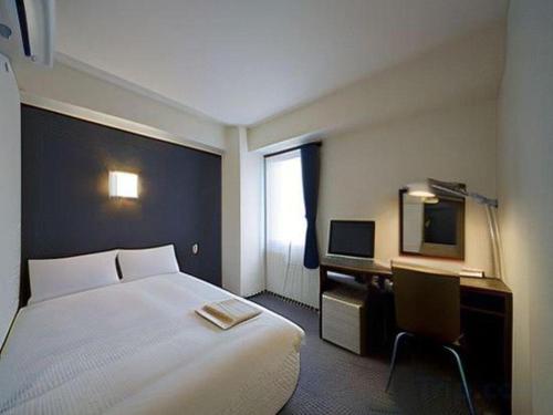 大分市にあるa.Suehiro Hotelのベッドと机があるホテルの部屋