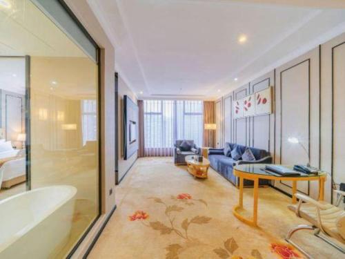 Una sala de estar con una bañera, un sofá y una mesa. en Golden Phoenix International Hotel, en Xiahuangtang