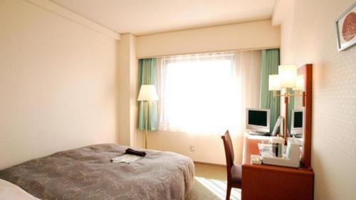 a hotel room with a bed and a desk and a window at Hotel Royal Hill Fukuchiyama and Spa in Fukuchiyama