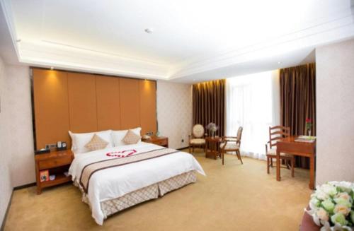 a hotel room with a large bed and a desk at Auspicious Hotel in Zhongshan