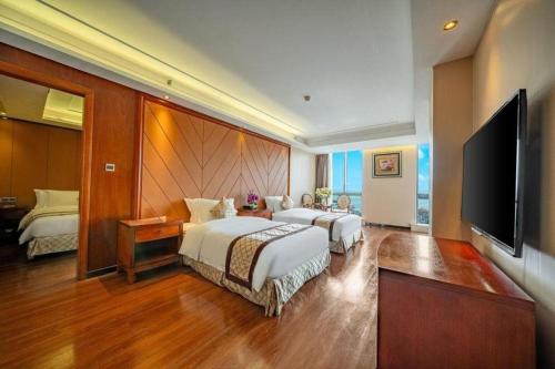 a hotel room with two beds and a flat screen tv at Auspicious Hotel in Zhongshan