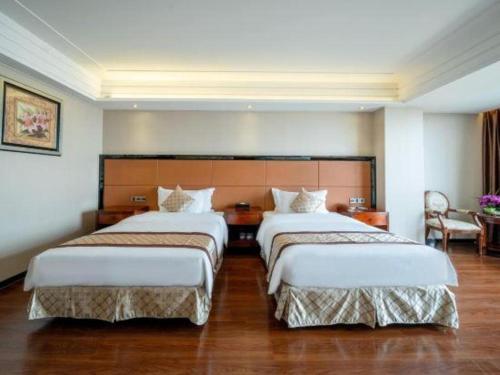 a hotel room with two beds and a table at Auspicious Hotel in Zhongshan