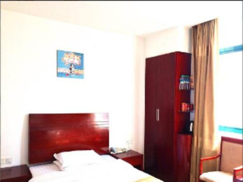 a bedroom with a bed and a red headboard at GreenTree Inn Shangrao Qianshan hekou old town Xinjiang longting shell hotel in Shangrao