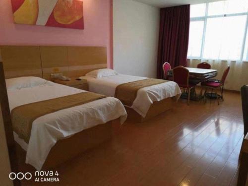 a hotel room with two beds and a table at GreenTree Inn Shangrao Qianshan hekou old town Xinjiang longting shell hotel in Shangrao