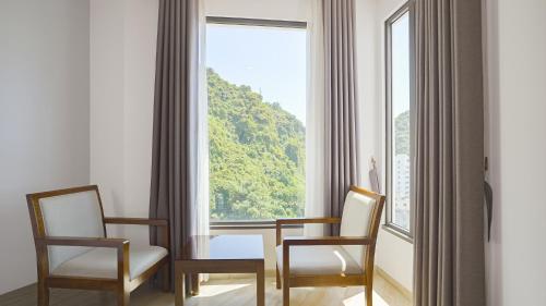 a room with a table and two chairs and a large window at Cat Ba Paradise Hotel - Sky Bar & Massage in Cat Ba