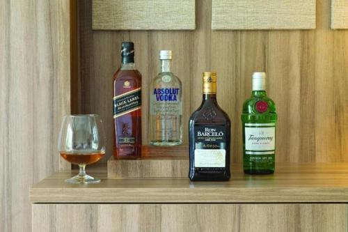 three bottles of whiskey and a glass on a shelf at EXCELLENCE PUNTA CANA - ALL INCLUSIVE - ADULTS ONLY in Punta Cana