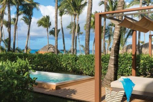 a swimming pool on a wooden deck with palm trees at EXCELLENCE PUNTA CANA - ALL INCLUSIVE - ADULTS ONLY in Punta Cana