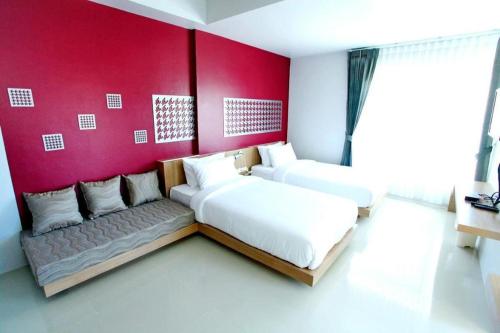 a bedroom with two beds and a red wall at Tonkok Hotel in Chiang Rai