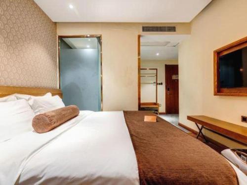 a bedroom with a large white bed and a desk at James Joyce Coffetel Qufu Tourist Center Gulou Street Sankong Scenic Spot in Jining