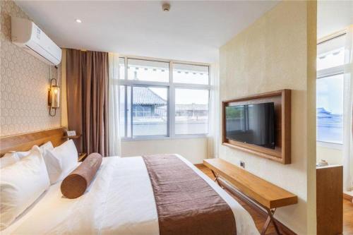a hotel room with a bed and a flat screen tv at James Joyce Coffetel Qufu Tourist Center Gulou Street Sankong Scenic Spot in Jining