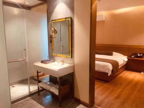a bathroom with a sink and a bed and a mirror at James Joyce Coffetel Qufu Tourist Center Gulou Street Sankong Scenic Spot in Jining