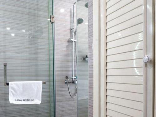 a shower with a white towel on a glass door at Xana Lite Anqing Yuexi Swan Squre Branch in Yuexi