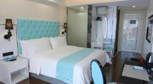 a bedroom with a large bed with a blue headboard at Xana Lite Anqing Yuexi Swan Squre Branch in Yuexi