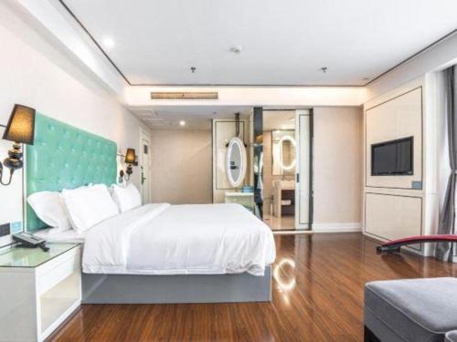 a bedroom with a large white bed and a television at Xana Lite Anqing Yuexi Swan Squre Branch in Yuexi