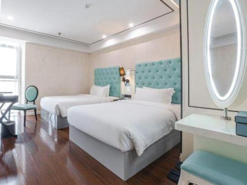a hotel room with two beds and a mirror at Xana Lite Anqing Yuexi Swan Squre Branch in Yuexi