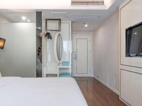 a white bedroom with a bed and a television at Xana Lite Anqing Yuexi Swan Squre Branch in Yuexi