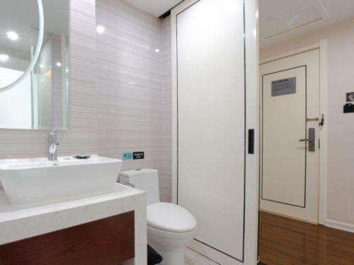 a bathroom with a white sink and a toilet at Xana Lite Anqing Yuexi Swan Squre Branch in Yuexi