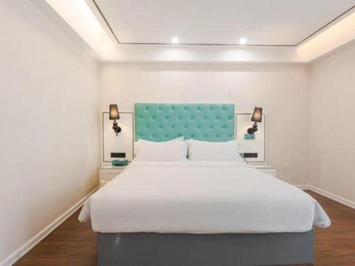 a bedroom with a large bed with a blue headboard at Xana Lite Anqing Yuexi Swan Squre Branch in Yuexi
