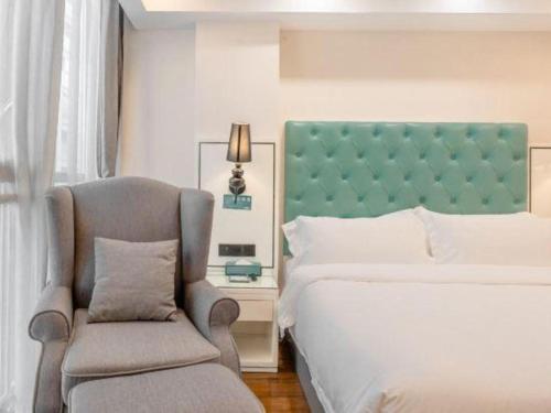 a bedroom with a bed and a chair at Xana Lite Anqing Yuexi Swan Squre Branch in Yuexi