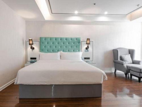 a bedroom with a large bed and a chair at Xana Lite Anqing Yuexi Swan Squre Branch in Yuexi
