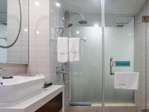 a bathroom with a sink and a glass shower at Xana Lite Anqing Yuexi Swan Squre Branch in Yuexi