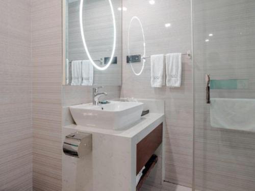 a white bathroom with a sink and a mirror at Xana Lite Anqing Yuexi Swan Squre Branch in Yuexi