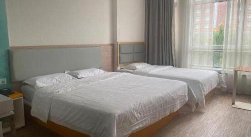 a bedroom with two beds and a large window at 7Days Inn Tianjin Airport NO.1 Bridge Branch in Tianjin