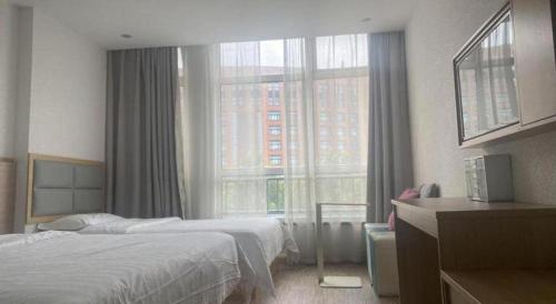 a bedroom with a bed and a large window at 7Days Inn Tianjin Airport NO.1 Bridge Branch in Tianjin
