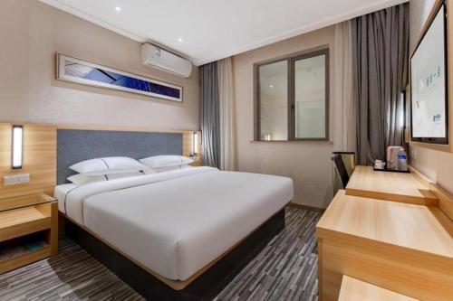 a hotel room with a large bed and a desk at City Comfort Inn Shanghai International Automobile City Tongji University in Anting Zhan
