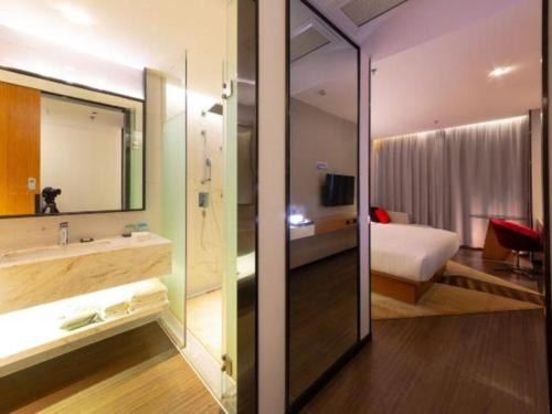 1 dormitorio con 1 cama y baño con lavamanos en Borrman Hotel Zhanjiang Xuwen Port Terminal, en Xuwen