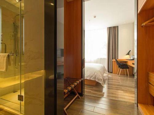 a bathroom with a shower and a bedroom with a bed at Borrman Hotel Jingzhou Jiangjin West Road Wanda Plaza Fantawild in Caoshi