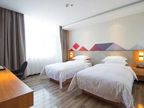 a hotel room with two beds and a table at Borrman Hotel Jingzhou Jiangjin West Road Wanda Plaza Fantawild in Caoshi