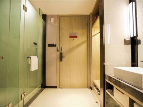 a bathroom with a shower and a door and a sink at Echarm Hotel Jingjiang Bus Passenger Station Fanggu Street in Jingjiang