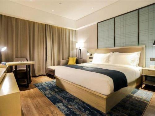 a hotel room with a large bed and a desk at Echarm Hotel Jingjiang Bus Passenger Station Fanggu Street in Jingjiang